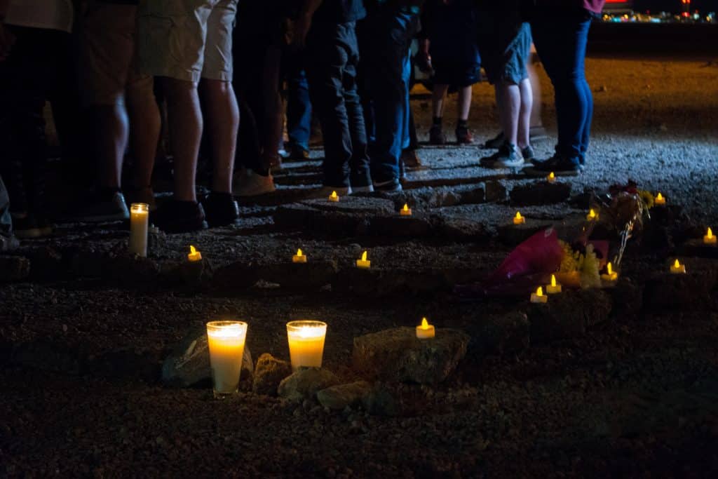 Rocks on the ground at a candlelight vigil spell out RIP.