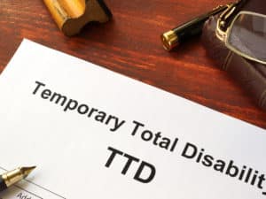 Temporary Total Disability (TTD) form on a wooden table.